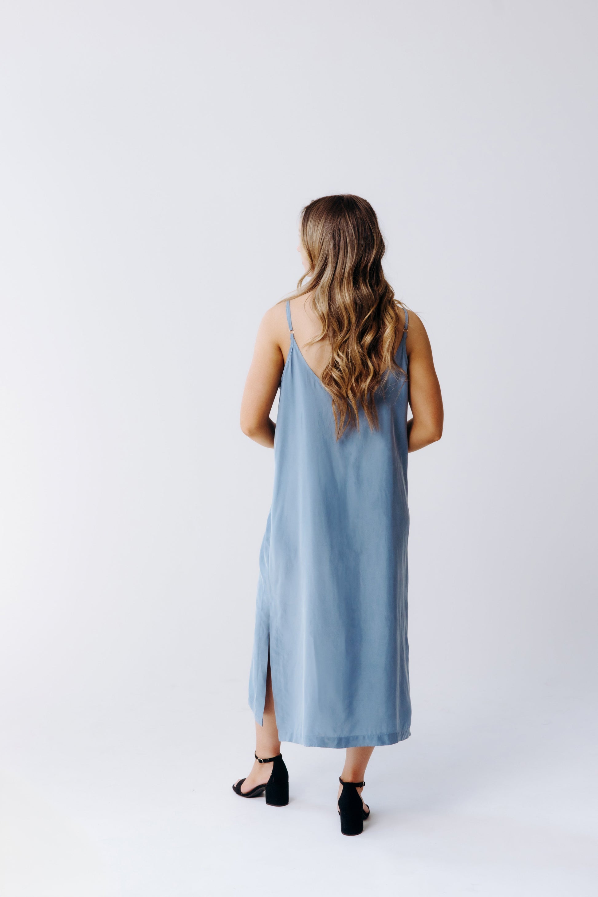 Woman wearing a light blue sleeveless dress on a white background