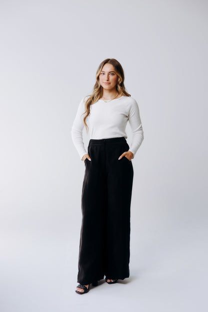 Woman wearing a white sweater and black pants on a white background