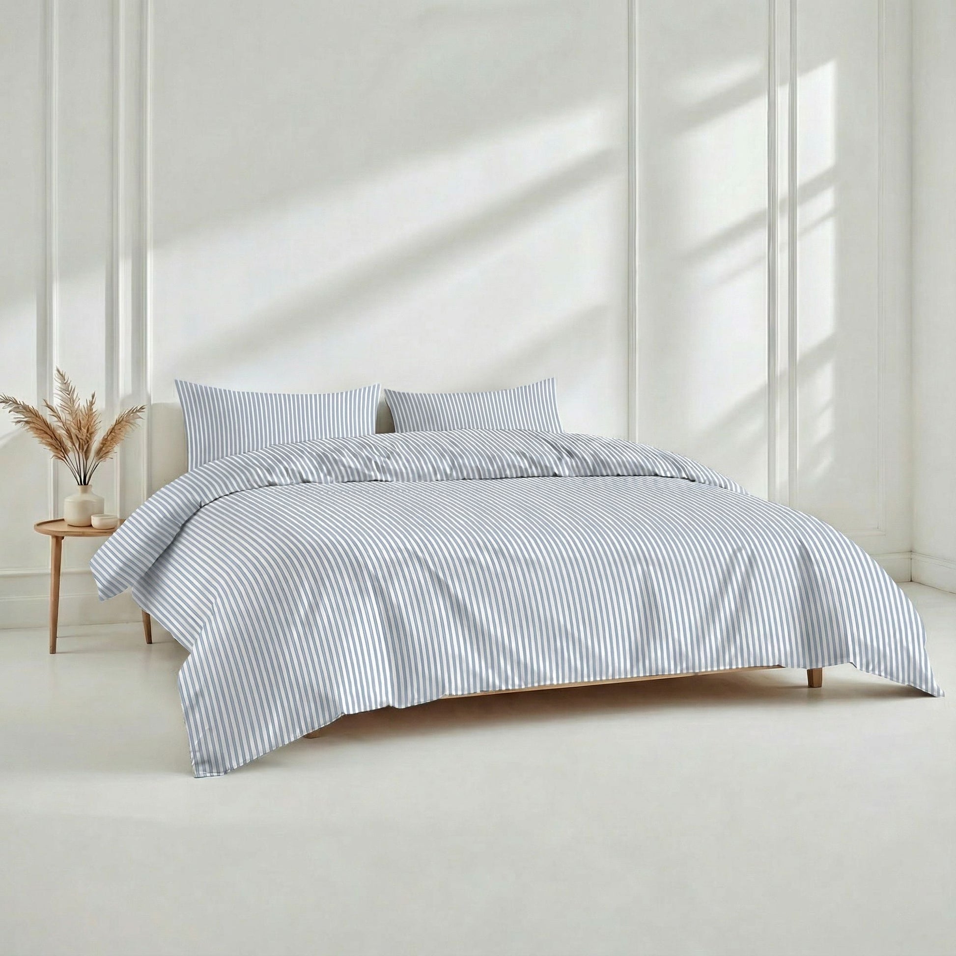 Bed with striped bedding in a bright room with sunlight filtering through.