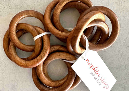 Four brown wood interlocking double-ring napkin rings with a white paper tag reading napkin rings set of four.