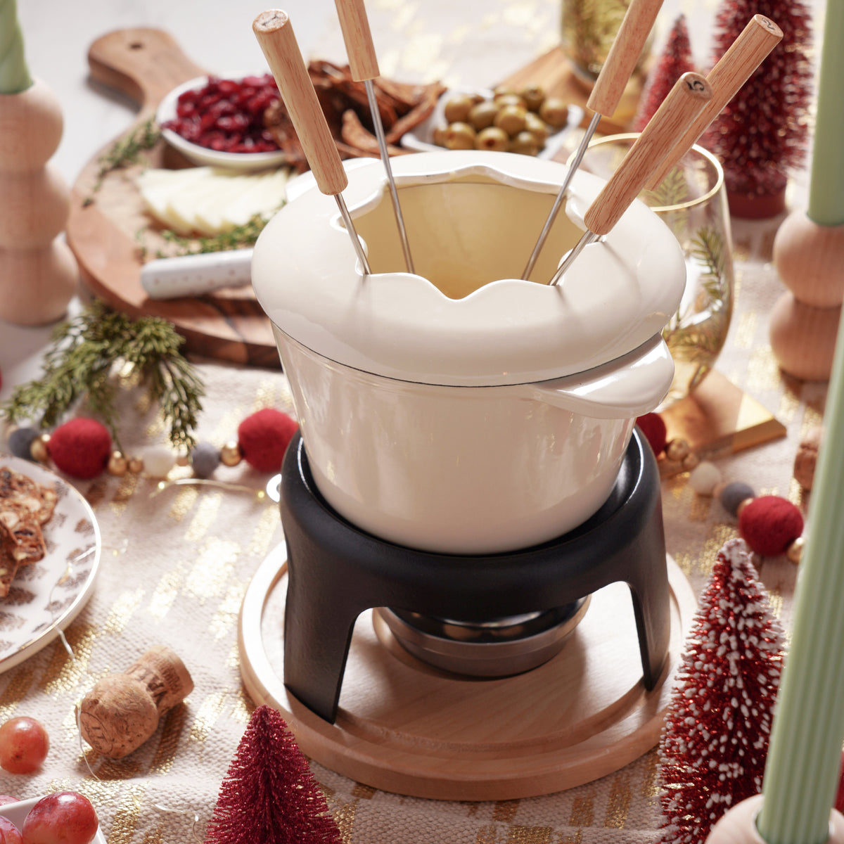 Fondue pot with wooden skewers on a festive table setting.