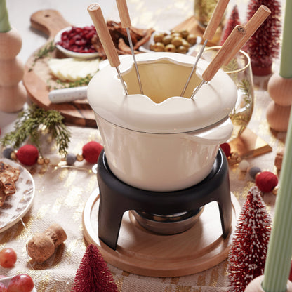 Fondue pot with wooden skewers on a festive table setting.